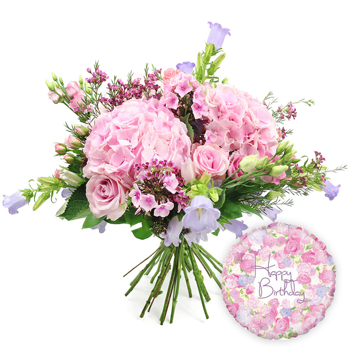 Set against a crisp, luminous white background, this image showcases a hand-tied birthday bouquet that feels both luxurious and gently romantic, as if prepared for a special celebration in one of Grove Park's characterful homes. The bouquet is centred on several large, domed heads of blush pink hydrangea, their countless petals packed closely together to create a billowing, cloud-like presence. These hydrangeas form the soft heart of the design, inviting the eye - and the imagination - to linger on their layered textures. Arranged thoughtfully among them are soft pink roses, chosen in varying degrees of openness. Some roses reveal their swirling centres, each petal unfurling in a classic spiral, while others remain more contained, the outer petals folding protectively around their cores. Fine sprays of tiny, bright fuchsia-pink filler flowers, like waxflower, run through the bouquet, their bead-like buds and small blossoms adding points of vivid colour and delicate texture that bring a natural, garden-inspired feel. Graceful stems of campanula rise a little above the main dome, bearing bell-shaped flowers in cool lavender and periwinkle blue, which introduce a soothing contrast to the pinks and add a vertical line reminiscent of wildflowers nodding in a breeze along Grove Park's footpaths. Encircling the blooms, layered green foliage lends volume and structure, with some leaves arching outward and others tucked in more closely, enhancing both shape and freshness. The stems are drawn together neatly at the base in a traditional hand-tied finish, ready to be slipped straight into a vase. To the lower right of the bouquet, a round, shimmering foil balloon adds a clear birthday message. Its design features a soft floral pattern of small roses and buds in pink, lavender, and cream, surrounding the words Happy Birthday written in graceful purple script. The pairing of bouquet and balloon creates a complete, joyful birthday gift image, ideal for illustrating flower delivery services in Grove Park and the surrounding riverside neighbourhoods.