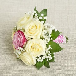 Picture clasping a petite bouquet, as inviting as a sunrise over Grove Park's gardens, with creamy ivory roses unfolding into generous blooms. Wisps of white baby's breath whisper through the arrangement, lending it a gentle, almost cloud-like delicacy. Off-center, a single magenta rose glows, its vivid presence recalling the bursts of colour found in the community's beloved open spaces and riverside walks. The deep emerald sheen of leafy greens supports the floral palette, creating a lush, natural balance. Each flower is at its freshest, petals velvety and full, exuding a subtle, romantic fragrance characteristic of Grove Park's finest florists. Wrapped in a satin pink ribbon and adorned with a spiral of luminous pearls, the stems are finished to perfection, echoing the care given to every local wedding detail. The bouquet's mood is both uplifting and heartfelt-a symbol of love and celebration befitting an elegant ceremony along the Thames or a joyful gathering at a neighbourhood venue. Crafted with passion for Grove Park's distinctive traditions, this floral creation speaks gently of devotion, community, and cherished memories.