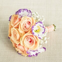 This bouquet tells the story of care and emotion-captured overhead as though resting on a beloved table in Grove Park after a sun-filled morning. An abundance of peach and apricot roses spread their velvety petals wide, the gentle blush at their centers glowing softly against crisp, oatmeal-hued linen. Around them, Lisianthus flowers in clean white reveal their distinctive, ruffled edges dipped in lively violet, a fresh note inspired by the eclectic charm of Burlington Lane. Wisps of Baby's Breath drift through the design, lightening the palette and adding a sense of airiness that echoes the openness of riverside walks nearby. Gathered at the base, the bouquet is held by a peach-pink satin ribbon adorned with delicate pearl beads-a nod to tradition and the personal touch of a local florist. Intended as a companion to special celebrations-a wedding reception, an engagement party, or an afternoon tea in Grove Park-the bouquet emanates an atmosphere of romance, grace, and contemporary flair, hand-delivered with expertise and warmth.