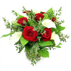 An elegant arrangement of crimson red roses and serene white calla lilies rests in a clear glass vase, isolated against a clean white background so that every detail of the bouquet feels calm and deliberate. At the center, a cluster of six to seven fully blossomed roses in deep, velvety red forms the heart of the design, each bloom layered with tightly curled petals that spiral inward, evoking classic romance that would not be out of place in a Grove Park townhouse. Interwoven among the roses are four or five calla lilies, their polished, trumpet-shaped petals folding gracefully around warm, yellowish spadices. These lilies bring a contemporary, sculptural quality, standing just above the roses and creating a gentle sense of height. Surrounding the main flowers, a lush collection of greenery spills outward: eucalyptus with silvery-blue, rounded leaves introduces a soft, airy texture, while broad, darker green foliage frames the bouquet and grounds it visually, as steady and reassuring as the leafy streets leading toward the River Thames. The stems are visible through the cylindrical glass vase, gathered neatly and submerged in clear water, with delicate ribbing around the base of the vase catching the light and adding a subtle decorative touch. Even, bright lighting illuminates the bouquet from above, emphasizing the rich saturation of the red petals, the creamy whiteness of the calla lilies, and the varied shades of green in the foliage, while casting only the faintest shadows. The result is a sophisticated floral composition, ideal for same-day delivery around Grove Park when you want to express love, mark a milestone celebration, or send a thoughtful, romantic gesture with understated elegance.