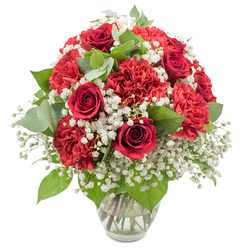A lush bouquet dominated by red and white blooms is captured in crisp, even light, presented in a simple clear glass vase that allows the colours to take centre stage against a flawless white background. The focal point is a cluster of deep red roses, their petals tightly spiralled and luxuriously soft-looking, each bloom a concentrated symbol of romance and heartfelt emotion. Encircling these roses are abundant red carnations, their pleated, ruffled petals creating generous volume and a textured surface that feels both playful and deeply traditional. Between the rich reds, clouds of white baby's breath drift gracefully, their tiny, airy blossoms softening the arrangement and introducing a sense of purity, innocence, and light. Interspersed throughout are gleaming dark green rose leaves and rounded eucalyptus foliage in muted grey-green tones, adding subtle coolness, visual structure, and a hint of natural calm, as if echoing the leafy, quiet atmosphere of Grove Park's residential streets. The stems, visible through the glass, are neatly cut and arranged in a fan, submerged in clear water that reflects the light and hints at freshness and careful handling. The bouquet forms a generous, rounded dome, appearing full from every angle, with the reds, whites, and greens perfectly balanced so that nothing feels too heavy or sparse. It is easy to imagine this arrangement arriving as a same-day delivery to a home near Grove Park Florist, placed on a dining table for an intimate celebration, or sitting on a mantelpiece in a flat overlooking the Thames path. The romantic red-and-white palette and classic styling make the bouquet ideal for anniversaries, Valentine's gestures, heartfelt thank-you gifts, or a comforting show of care during more reflective moments.