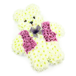 In this image, a beautifully arranged teddy bear floral tribute sits serenely against a crisp white backdrop, radiating a sense of comfort that would resonate with families across Grove Park. Every part of the bear-from its rounded head and perky ears to its plump paws-is crafted from soft white chrysanthemums, the blooms tightly grouped so that the surface appears plush and velvety, as though mimicking the feel of a much-loved toy. The head is slightly tilted forward, giving the impression that the bear is leaning in with quiet attentiveness. Two tiny, dark floral accents create the eyes, and a neat black nose is placed just beneath, shaping an expression that is both gentle and protective. Running across the bear's chest is a vibrant waistcoat made from deeper pink and mauve blossoms, whose petals are a touch more open and ruffled than the chrysanthemums. This splash of colour brings warmth to the design, echoing the cheerful gardens and riverside blooms often seen near Grove Park station or along the towpath towards Kew. At the neckline, a small bow of translucent purple netting is tied with care, its airy layers catching the light and providing a whimsical finishing detail. The arrangement is lit evenly, allowing each petal and contour to be clearly defined without distraction. Created as a funeral or remembrance tribute, this floral teddy captures both innocence and devotion, making it especially poignant for services where families wish to honour a child or celebrate tender memories. It feels like a heartfelt, handcrafted keepsake, the kind local residents might ask Grove Park Florist to deliver for a final, loving goodbye.