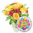 A vibrant, heartening Get Well Soon gift ensemble set against a clean white backdrop, arranged with the quiet confidence of a neighbourhood florist. On the left a lush bouquet sits in a clear glass vase, stems visible through the water, composed of soft orange and deep yellow roses whose spiraling petals open like warm sunlit cups. Bright yellow gerbera daisies push their cheerful faces forward, while rich burgundy or maroon carnations introduce a ruffled, velvety texture that grounds the composition. Sprays of delicate white alstroemeria float between the bolder blooms, adding a light, airy punctuation and a faint sweet scent that lifts the bouquet. Glossy, verdant foliage cradles every stem, its varied leaf shapes adding depth and a fresh, dewy green that feels like early morning at Grove Park Nature Reserve. To the lower right a shiny, round Mylar foil balloon partially overlaps the bouquet; its silvery surface reflects soft studio light and showcases a playful cluster of cartoon-style balloons in blue, purple, green, pink, and yellow, some patterned with stripes, polka dots and checkerboard motifs. Bold yellow-and-blue lettering with a subtle shadow proclaims the sentiment Get Well Soon across the centre, surrounded by small starburst graphics along the white border and a tiny KALEIDOSCOPE logo at the bottom edge. The overall effect is uplifting and comforting - an arrangement that smells faintly of citrus and cut greens, radiates hope, and reads as a sincere, hand-tended wish for recovery ideal for sending across Grove Park, to nearby Lee Green or Hither Green as a thoughtful hospital or home delivery.