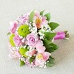 Photographed under gentle light against a pale, textured background, this elegant bouquet, artfully arranged in Grove Park, harmoniously blends soft pink roses, radiant lime-green button chrysanthemums, and airy clusters of white gypsophila-all complemented by lush foliage for a refined local wedding touch. The roses, featuring classic tightly layered pink petals, embody romance and purity, perfect for milestones celebrated in Grove Park's historic halls. Sprightly green pompon chrysanthemums nestle alongside, their rounded shapes and vivid coloring injecting excitement and cheer as lively as a stroll in Dukes Meadows. The bouquet's sophistication is elevated by pink alstroemeria, their slender petals elegantly speckled in gold and maroon, offering a gentle exotic touch. Ethereal clouds of baby's breath are thoughtfully woven throughout, creating an almost weightless effect, softening the design, and connecting each element with a breeze-like cohesion. Framing the arrangement, deep green leaves mirror the verdant scenery found around Grove Park's riverside paths. The stems are meticulously bound together with a richly hued fuchsia satin ribbon, forming a graceful handle and providing a burst of modern color. Perfectly fresh and ready for delivery across Grove Park, this bouquet exemplifies true local craftsmanship and is destined to enhance weddings, special events, or offer a heartfelt gesture of appreciation.