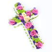 In this image, a cross-shaped floral tribute is set against a clean, pure white background, captured from a slightly overhead view so its craftsmanship and volume are easy to imagine by touch. The cross is defined by a fine border of densely packed white spray chrysanthemums, their tiny petals forming a plush, cloud-like edge that gently softens the strong lines of the Christian symbol. From beneath this snowy fringe, a narrow band of pale green ribbon or folded foliage appears, circling the entire outline with a subtle, tailored finish reminiscent of the well-kept gardens and leafy paths around Grove Park. The central area of the cross is richly filled with a tapestry of blooms. Large roses in vivid hot pink and soft, creamy lemon tones are scattered with care along the length and arms, each bloom fully open to reveal spirals of velvety petals that suggest affection and cherished memories. Among these, lime-green button chrysanthemums dot the arrangement, their small, rounded heads bringing a modern, textural contrast and a bright, fresh energy. Threaded through the spaces are smaller, deep purple or violet flowers-probably lisianthus or statice-that add depth and a softly sombre note, making the tribute feel appropriate for a funeral service or memorial gathering. The cross is angled from the upper left towards the lower right, which enhances its dimensionality and draws the viewer's eye along its length. Illuminated with bright, even light, each petal, ribbon fold, and cushiony chrysanthemum is sharply defined, conveying the skill of the florist. This floral cross would feel at home in any Grove Park church or chapel, offering comfort, faith, and a gentle celebration of a loved one's life.