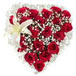 A meticulously shaped heart of flowers sits against a crisp white background, its silhouette created from a dense tapestry of deep crimson roses and feather-soft white gypsophila. Dozens of velvety red roses-some tight as blushing buds, others unfurling into full, ruffled blooms-are packed so closely they read as a single, passionate field of colour. Tiny, star-like clusters of baby's breath are woven throughout and halo the heart's edge, their fragile white sparks lightening the overall weight and lending an airy, cloud-like softness between the heavier rose heads. Nestled in the upper-left curve, a single pristine white lily opens with broad, waxy petals tipped by a faint creamy yellow at the throat; its yellow-orange stamens punctuate the composition with a warm, sculptural accent. The lighting is soft and even, picking out the roses' velvet texture and the lily's satin sheen while preserving gentle shadow in the folds of petals-an effect that makes the arrangement feel both intimate and refined. Scents mingle in the imagination: the sweet, heady perfume of red roses balanced by the cool, green suggestion of lily and the almost powdery whisper of gypsophila. This arrangement reads as a classic declaration of lasting affection-suitable for anniversaries, Valentine's Day, or a formal tribute-crafted with traditional technique and an eye for romantic storytelling. Presented by a local Grove Park florist, it evokes the quiet care of neighbourhood floristry: a piece you could imagine being handed over beside Grove Park station, or leaving the studio on Baring Road for delivery to a loved one nearby.